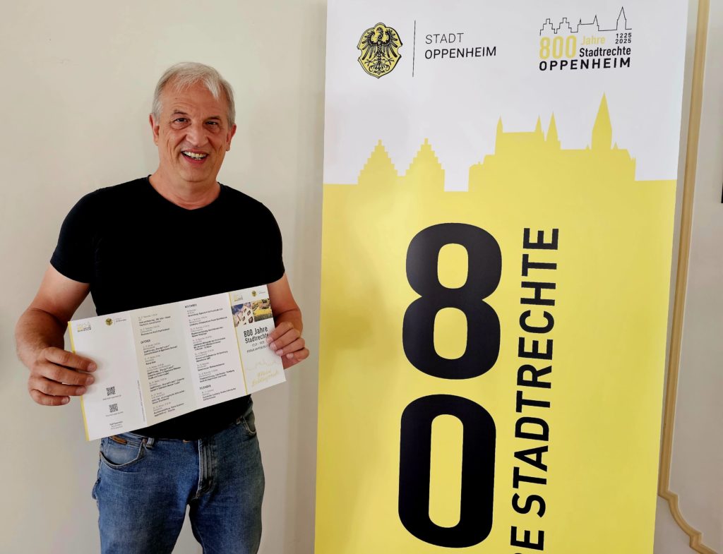 Stephan Arnold präsentiert den Flyer zur 800-Jahr-Feier der Stadtrechte Oppenheim – Einblick in ein besonderes Jubiläum.