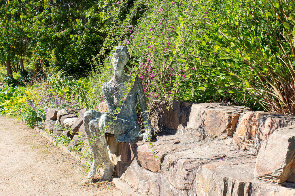 Skulptur einer Frau, die die Natur auf einer Bank im Botanischen Garten Mainz genießt