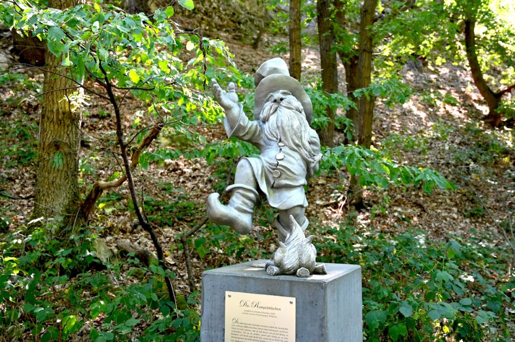 Rumpelstilzchen-Figur am Märchenweg im Wald